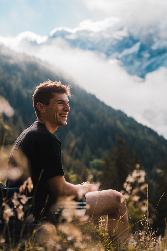Man enjoying freedom to find their own path after successful coaching while resting on a sunny mountainside